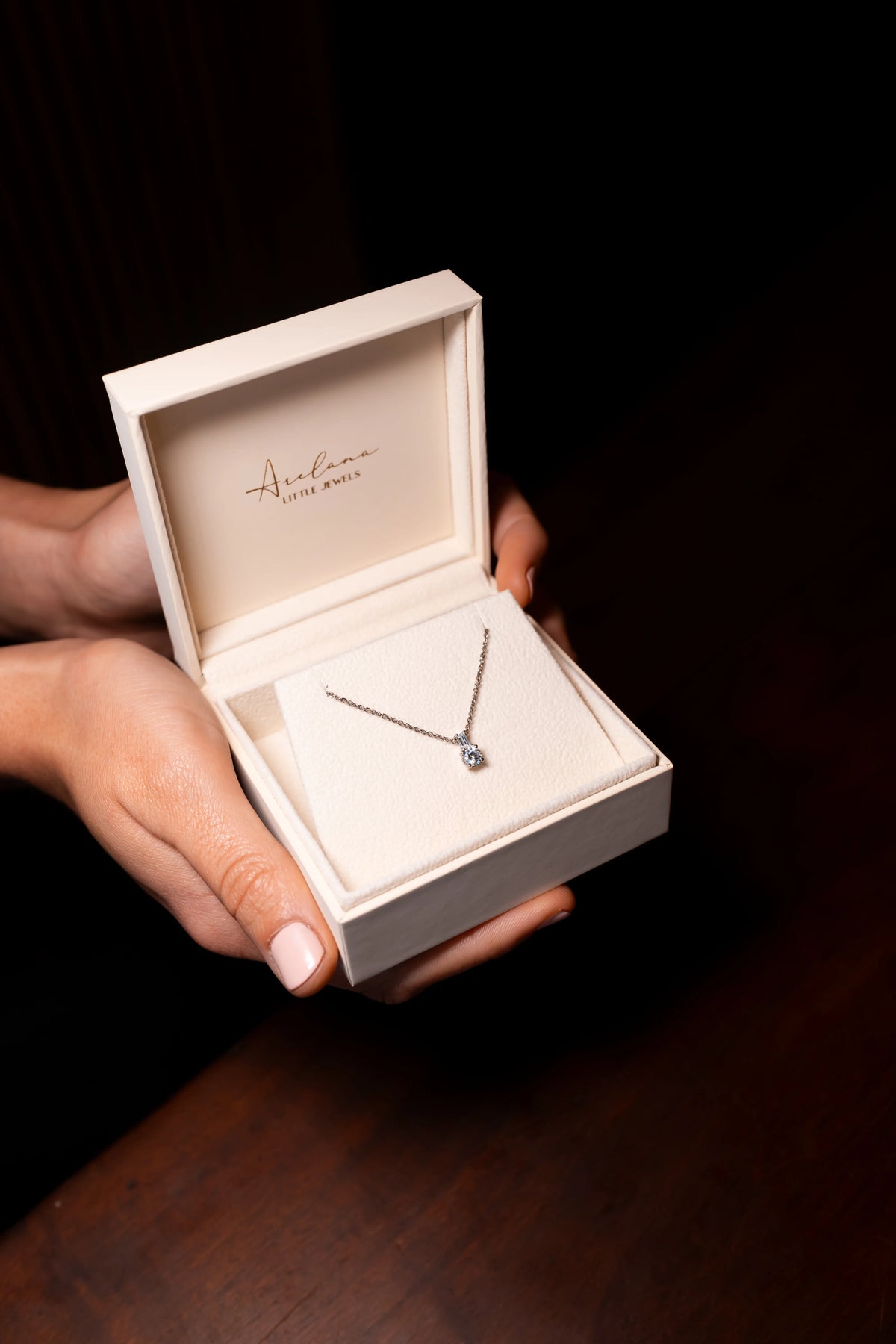 Colgante de diamante con baguete en su estuche de Arelana, sostenido entre las manos