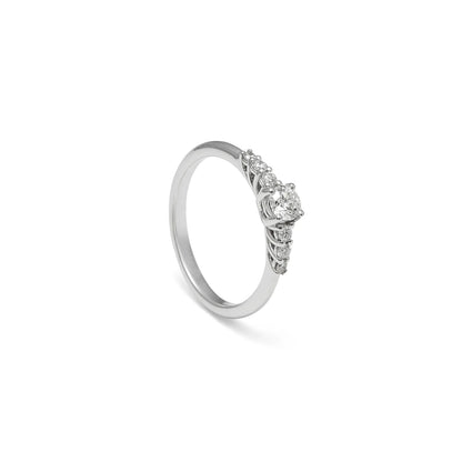 Anillo de compromiso con frente de luz. El centro destacado se acompaña de pequeños detalles luminosos laterales.