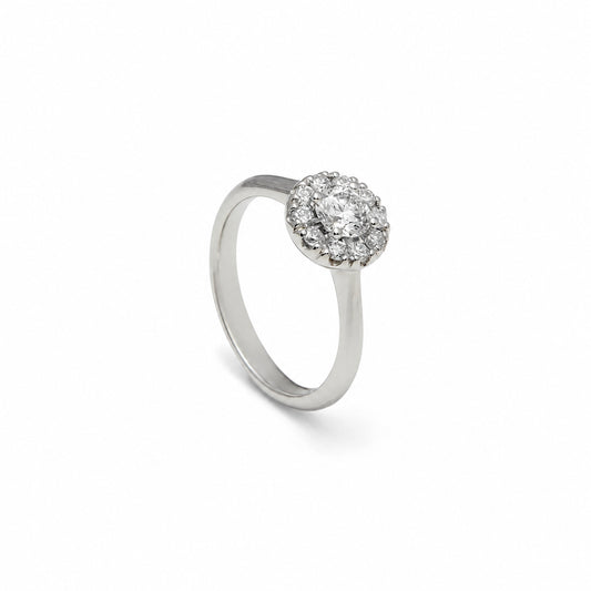 Anillo rosetón de aro liso. El centro incoloro queda rodeado por pequeñas piedras luminosas.