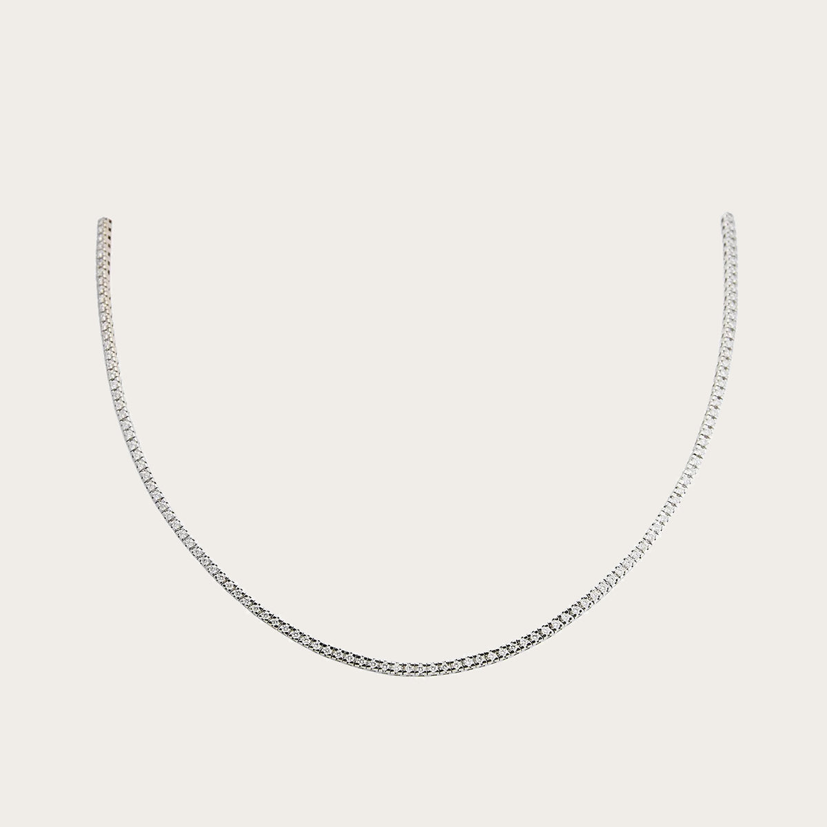 Collar rivière de contorno fino. Las pequeñas piedras incoloras se suceden a lo largo del tramo visible.