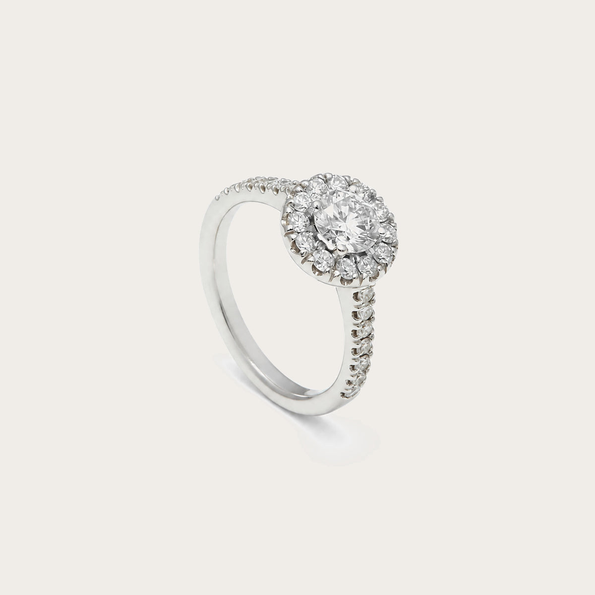 Anillo rosetón con aro luminoso. Una orla de pequeñas piedras perfila el centro incoloro.
