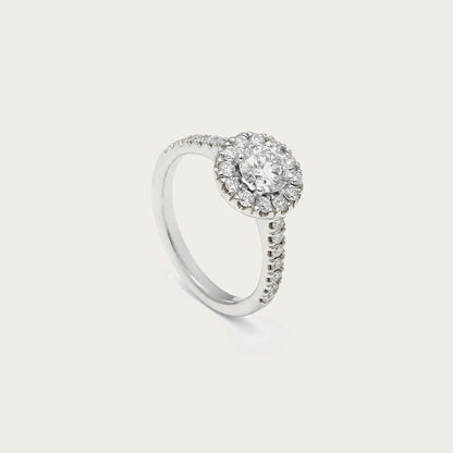 Anillo rosetón con aro luminoso. Una orla de pequeñas piedras perfila el centro incoloro.