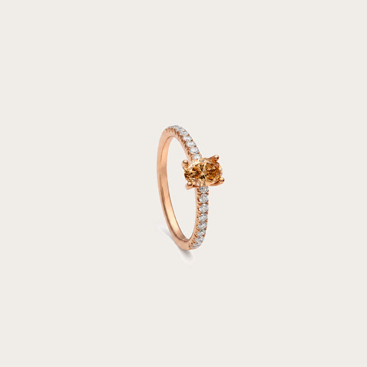 Anillo de diamante oval color coñac. La montura central presenta garras visibles alrededor del contorno ovalado.