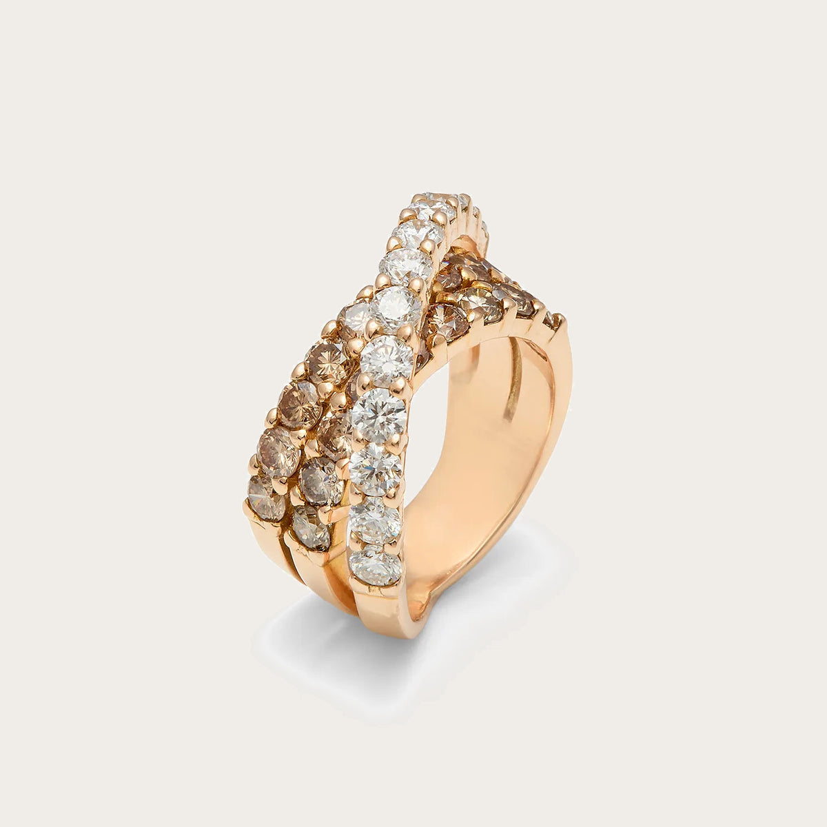 Anillo de bandas cruzadas y tonos cálidos. Una línea de piedras incoloras atraviesa el frente de tono dorado.