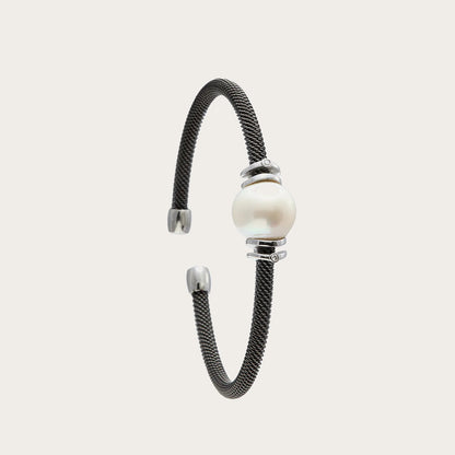 Pulsera de acero con centro claro y bandas. Las superficies lisas acompañan los reflejos suaves del motivo redondo.