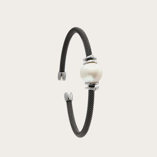 Pulsera de acero con centro claro y bandas. Las superficies lisas acompañan los reflejos suaves del motivo redondo.