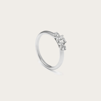 Anillo de compromiso con aro liso. Las garras de la montura enmarcan la piedra central incolora.