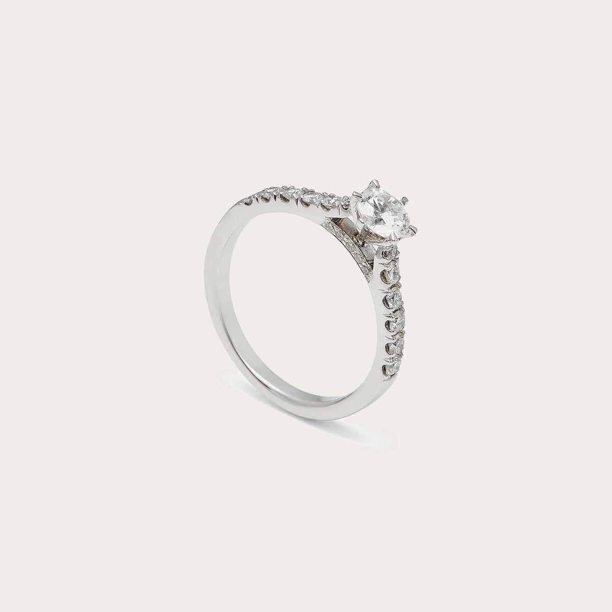 Anillo de compromiso con hombros luminosos. Las pequeñas piedras siguen la parte superior de la banda.
