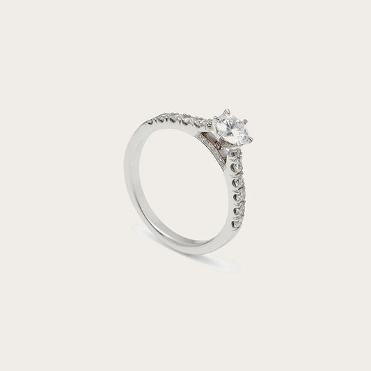Anillo de compromiso con hombros luminosos. Las pequeñas piedras siguen la parte superior de la banda.