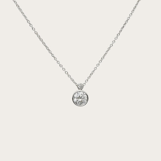 Colgante solitario de círculo luminoso. Un borde fino de tono plateado perfila la piedra incolora.