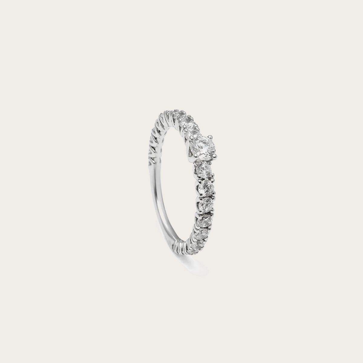 Anillo de compromiso de contorno luminoso. Las piedras incoloras se suceden en el tramo visible del aro.