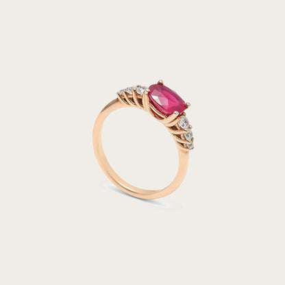 Anillo de centro rosado y hombros de luz. Las garras visibles enmarcan la piedra alargada del frente.