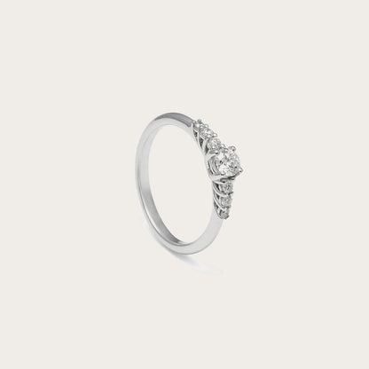 Anillo de compromiso con frente de luz. El centro destacado se acompaña de pequeños detalles luminosos laterales.