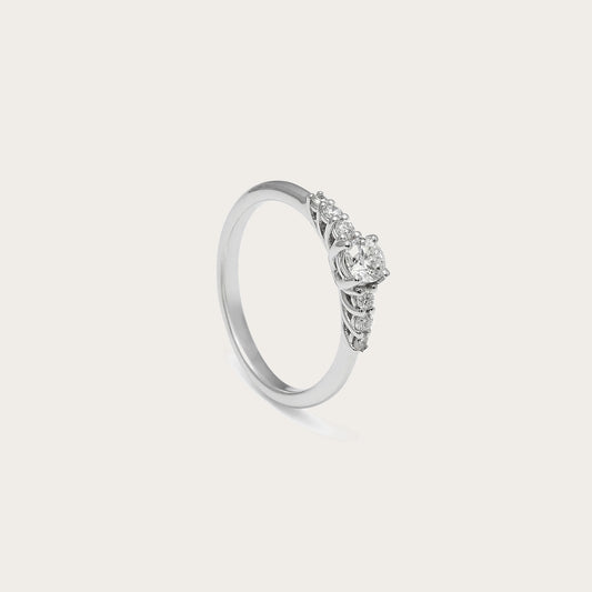 Anillo de compromiso con frente de luz. El centro destacado se acompaña de pequeños detalles luminosos laterales.