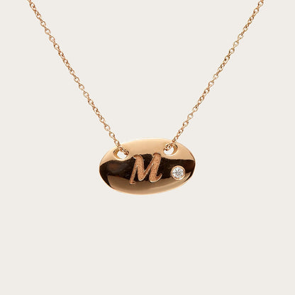 Colgante oval de inicial. La letra M destaca sobre la superficie lisa del motivo.