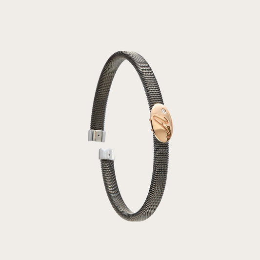 Pulsera de acero con óvalo dorado. El motivo presenta líneas interiores visibles.