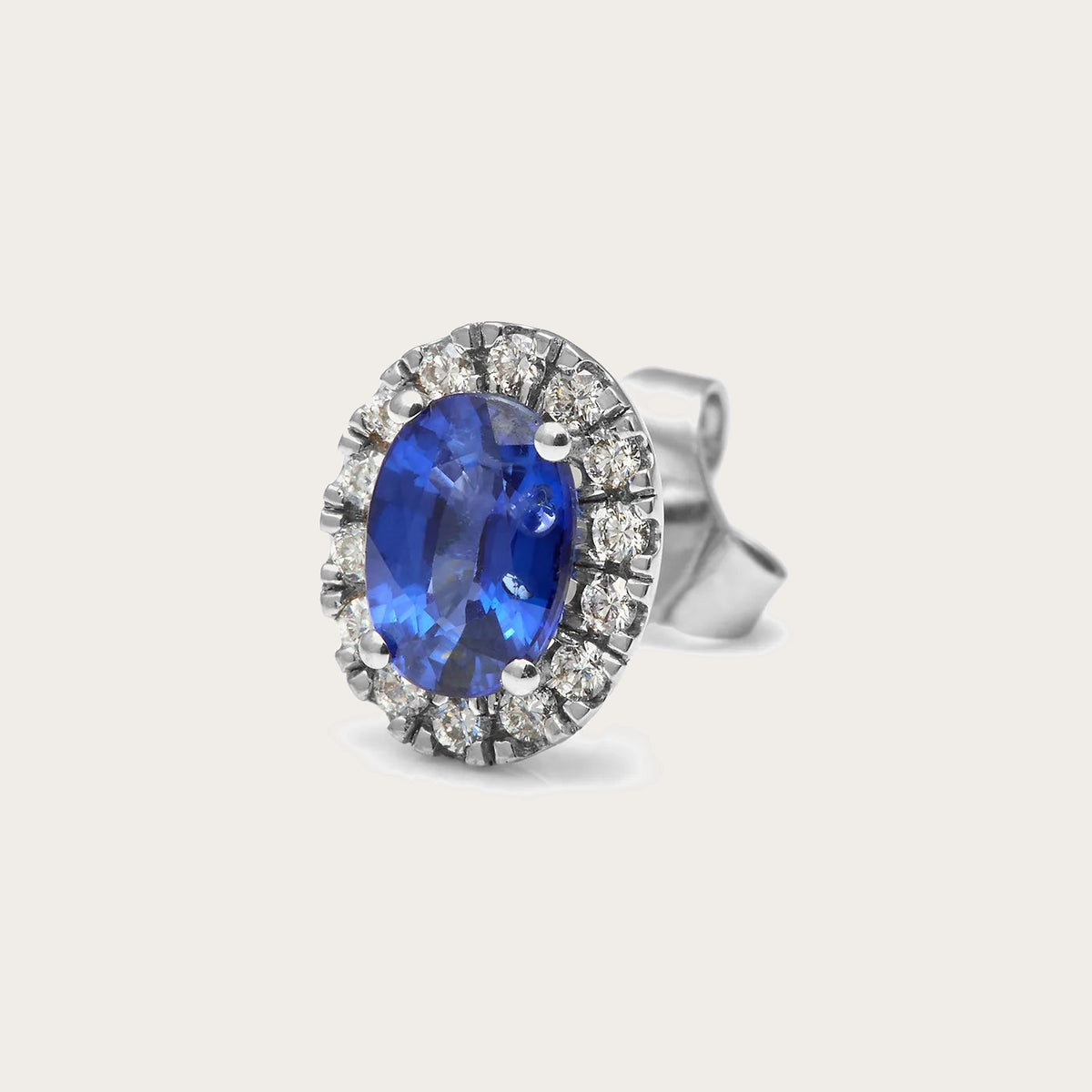 Pendientes de centro azul oval y halo. Las piedras incoloras del contorno se presentan en monturas visibles.