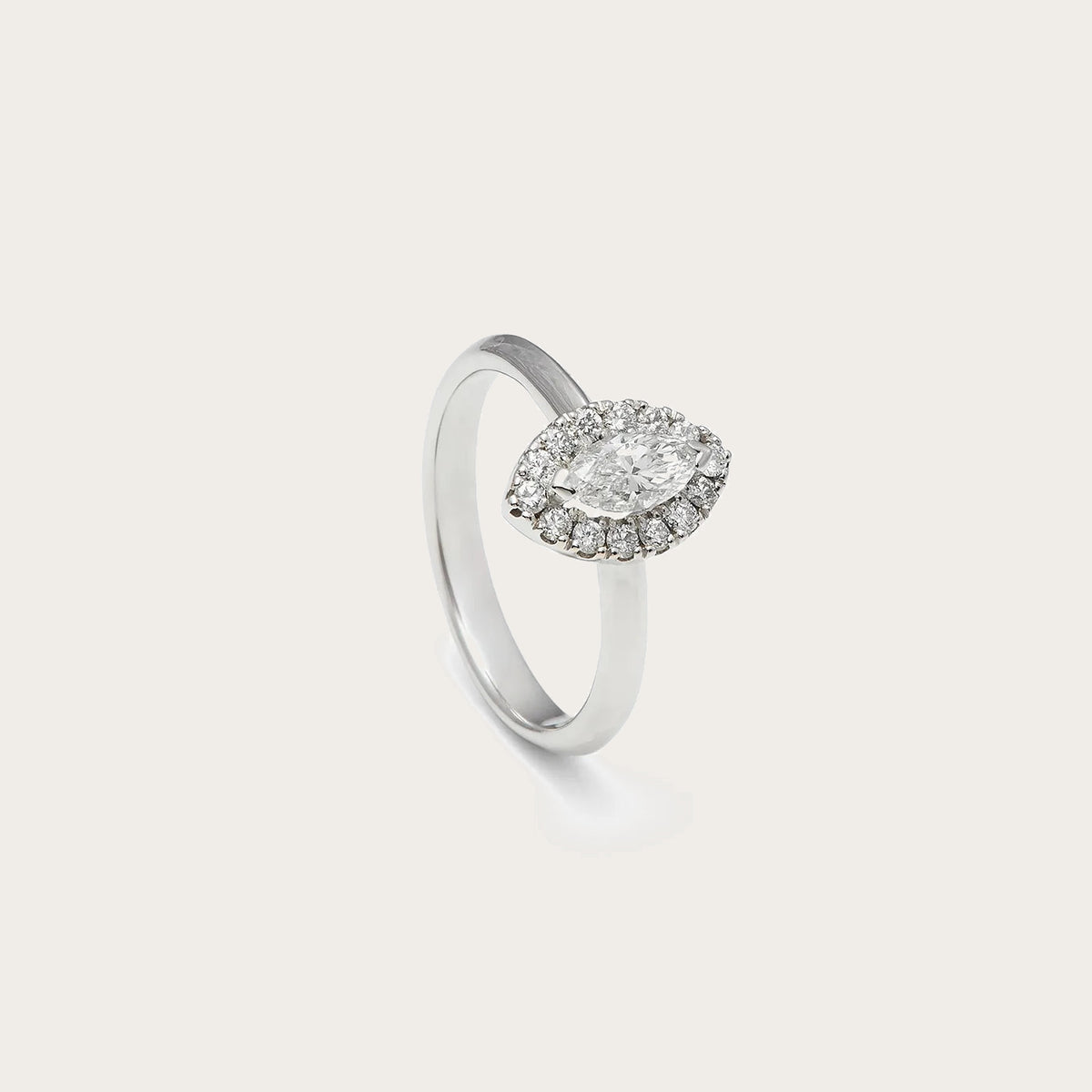 Anillo de compromiso con frente ovalado. Una orla de pequeñas piedras perfila el centro del diseño.