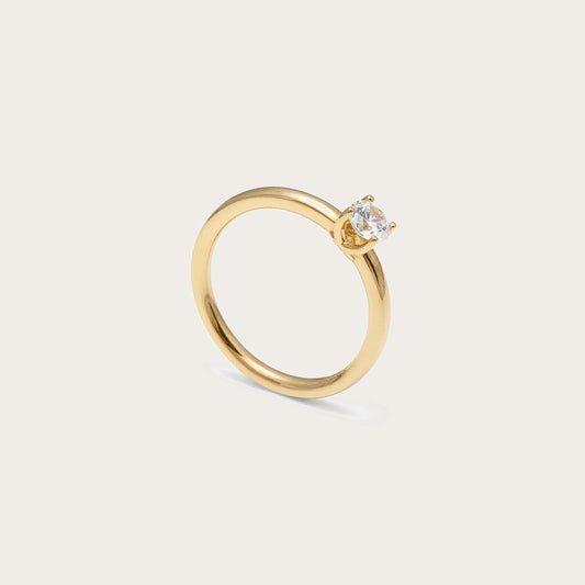 Solitario de tono dorado y centro de luz. La montura central presenta garras visibles de contorno curvo.