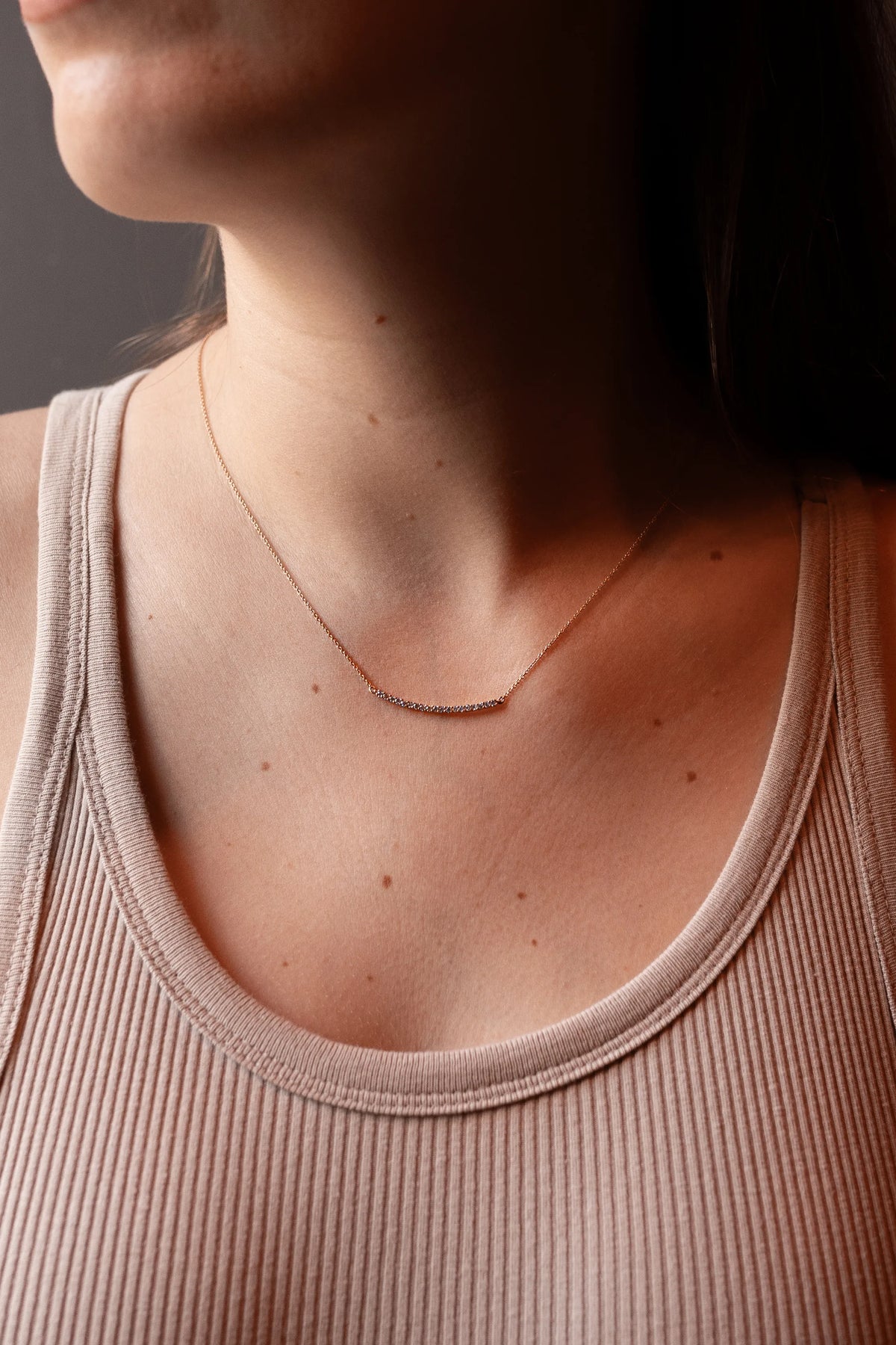 Colgante de barra curva con diamantes en oro rosa, puesto sobre el escote