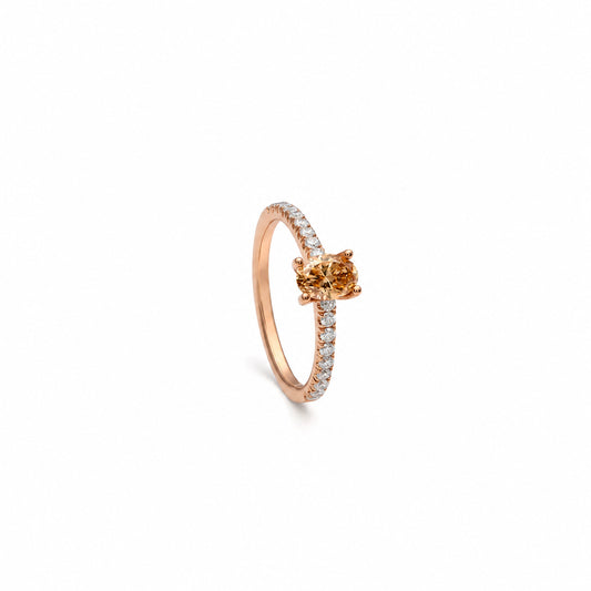 Anillo de diamante oval color coñac. La montura central presenta garras visibles alrededor del contorno ovalado.